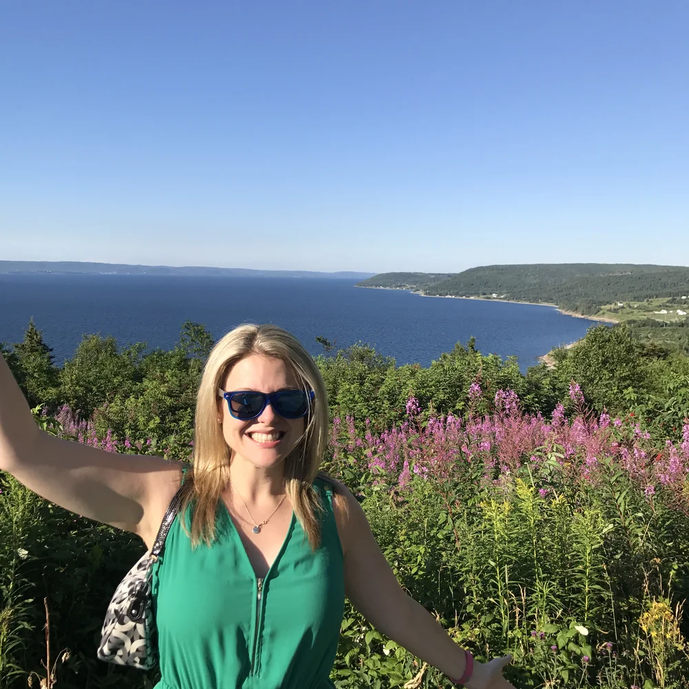 Dr. Perchaluk on a summer trail beside tall pink wildflowers overlooking a lake
